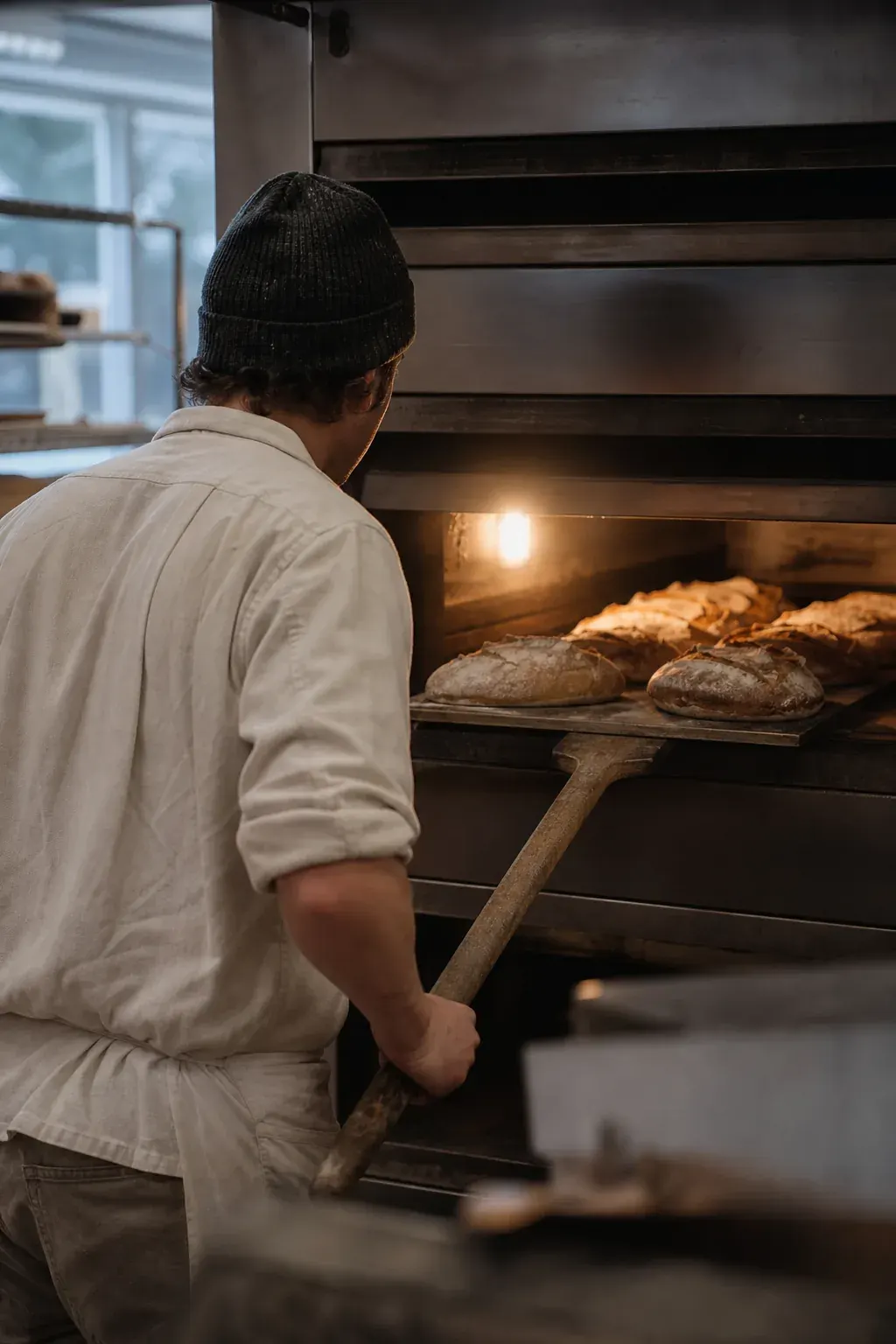 Baker pulling loaves from a deck oven