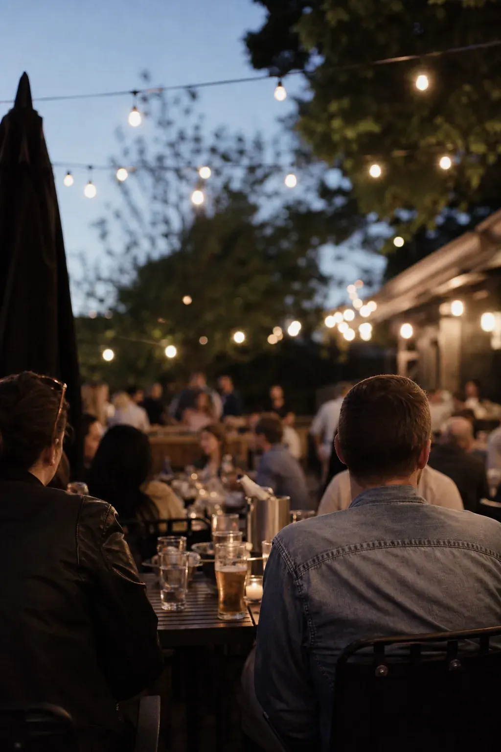 Busy bar patio on a summer evening under string lights