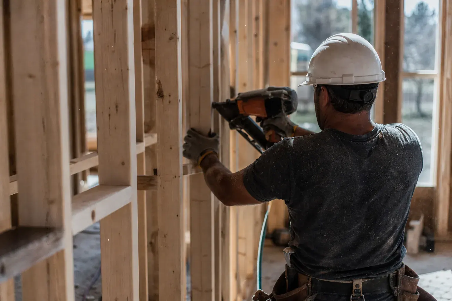 Carpenter framing a wall with a nail gun