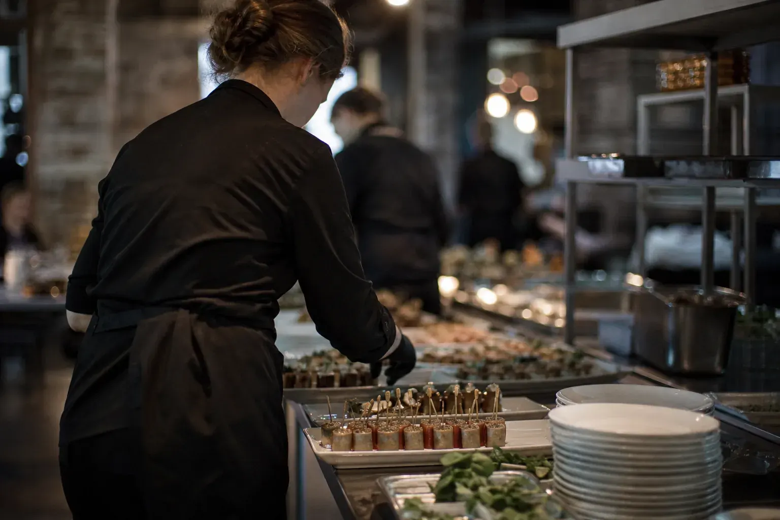 Catering staff plating hors d'oeuvres in an event kitchen