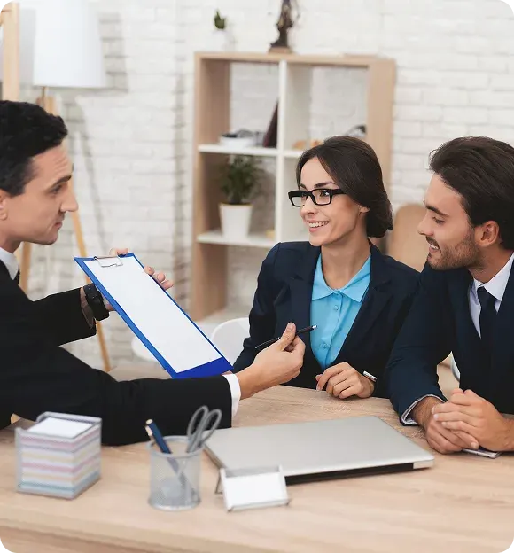 Man showing a clipboard to a smiling couple, likely during a business or consultation meeting in a modern office.