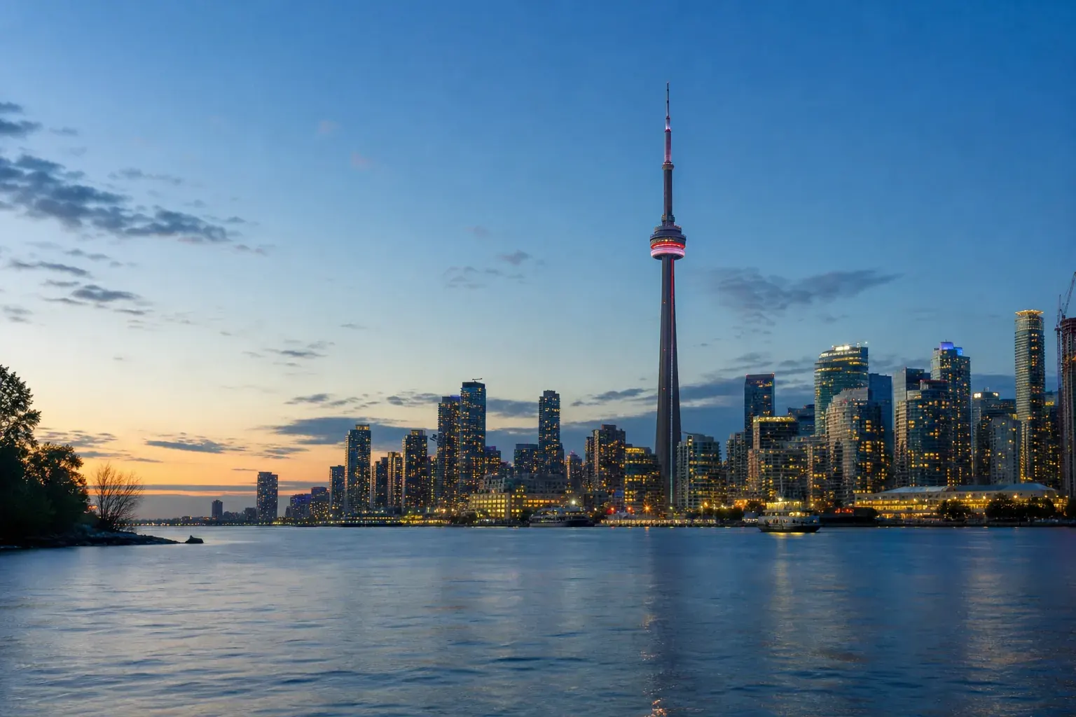 Toronto skyline and CN Tower at dusk across Lake Ontario